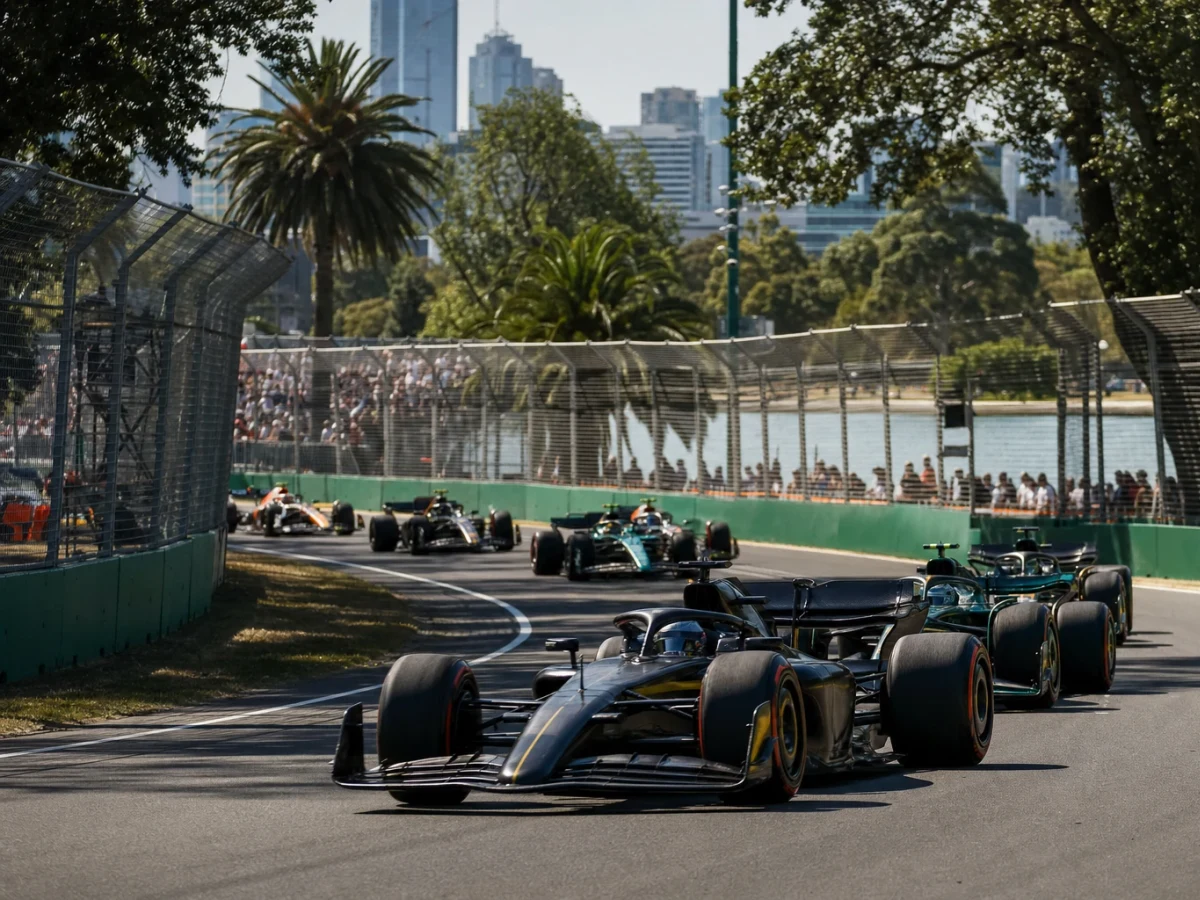 Formel 1-bilar genom en snabb kurva på en parkbana i solsken.