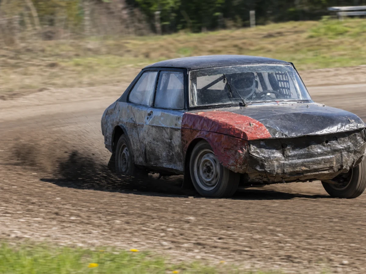 Folkracebilar i tät kamp på en grusbana med lera och damm