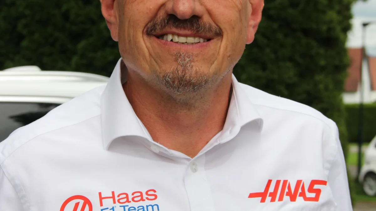 Person i teamkläder gestikulerar vid depåväggen under en formel 1-tävling.