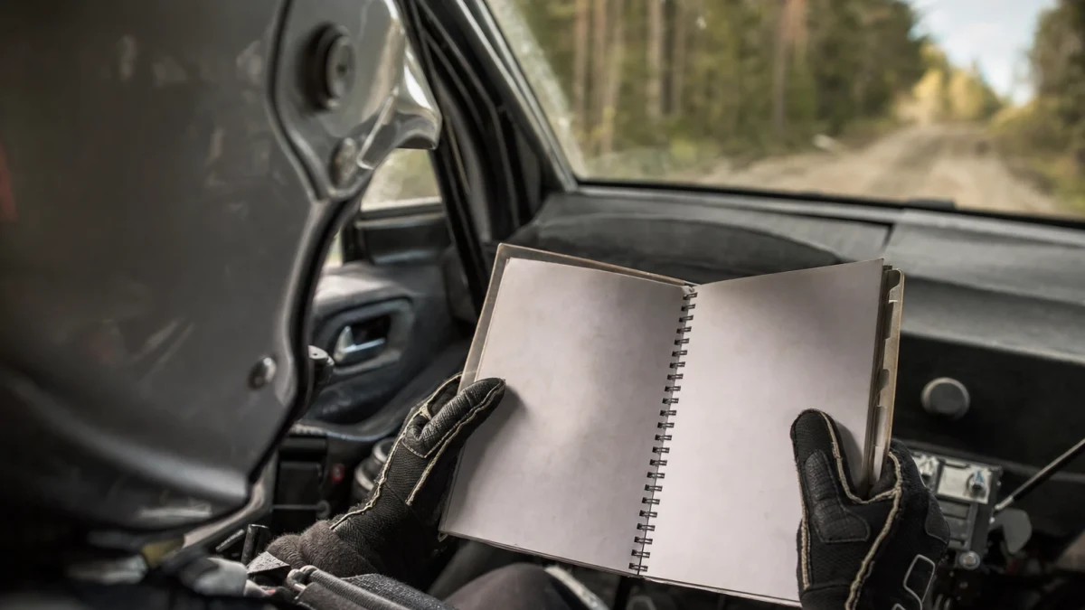 Kartläsare i passagerarsätet läser noter under en rallytävling