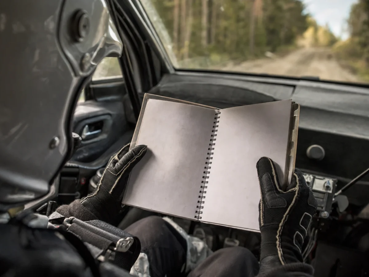 Kartläsare i passagerarsätet läser noter under en rallytävling