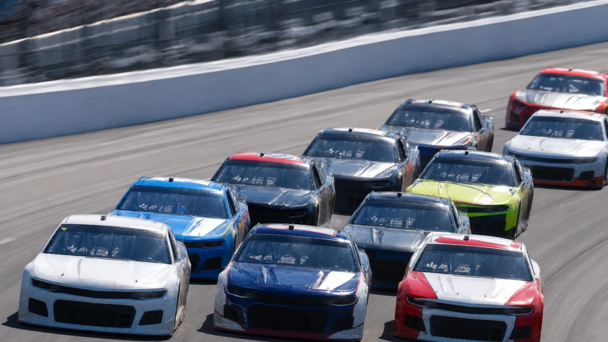 NASCAR-bilar i tät klunga sida vid sida på en oval under ett lopp