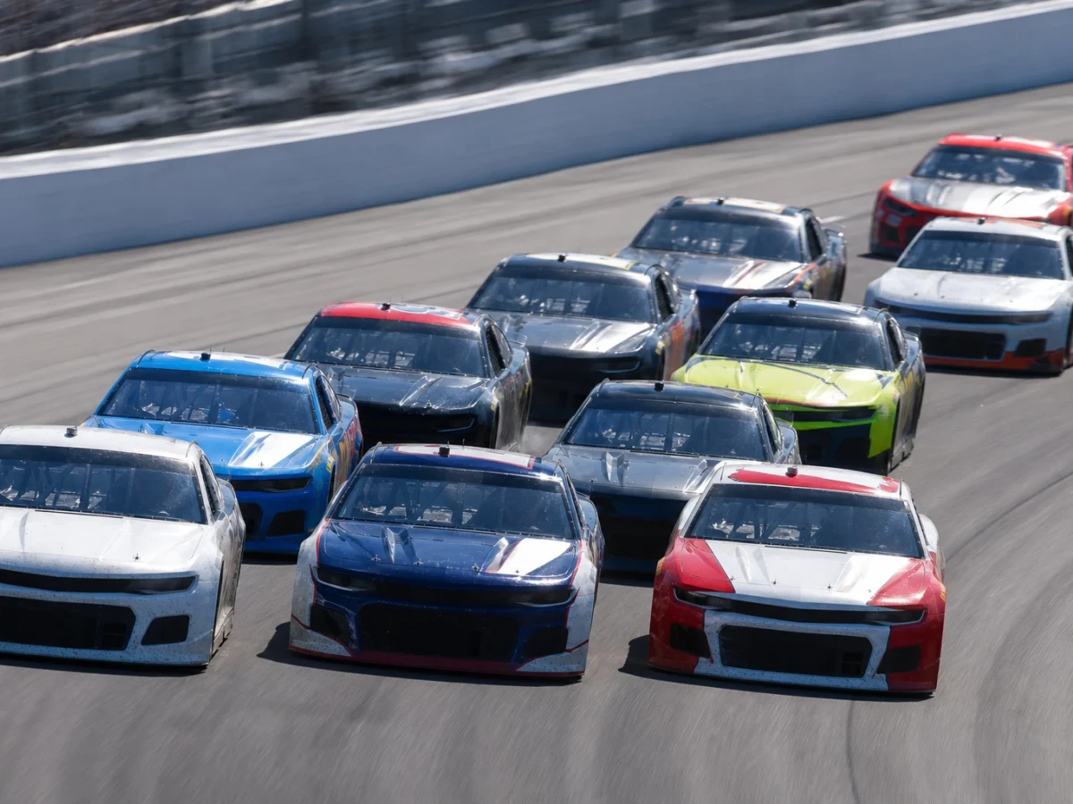 NASCAR-bilar i tät klunga sida vid sida på en oval under ett lopp